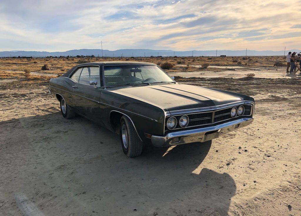 A sedan parked at a deserted area under a cloudy sky